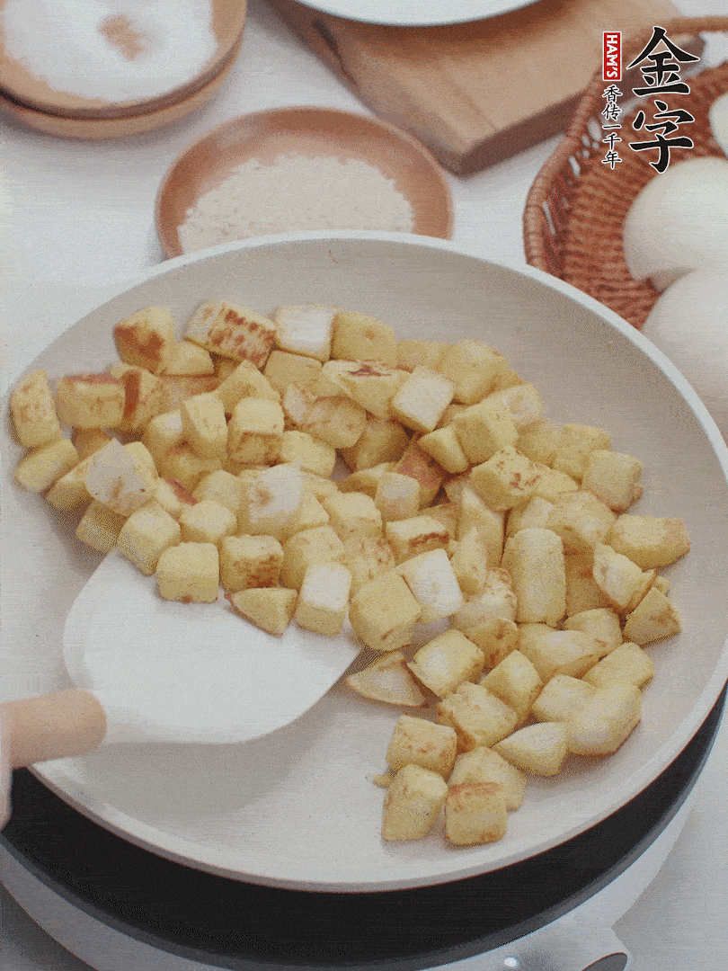 起鍋熱油，倒入饅頭丁，小火煎至蛋液凝固定型再翻面，饅頭丁部煎至金黃時(shí)盛起待用。