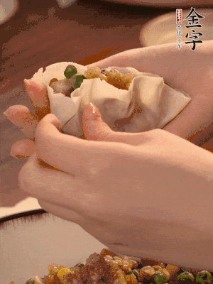 取一大勺餡料放進(jìn)餃子皮里，用大拇指按住頂部餡料，再用虎口掐出形狀。